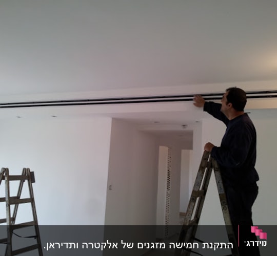 אדם על סולם מתקין מזגן בתקרה